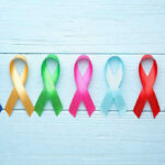 Immune System HACKED—Tumor Tactic Unveiled Colorful awareness ribbons on light wooden background