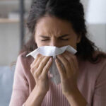 UV Breakthrough Nukes Allergens—Instantly Woman sneezing into a tissue indoors