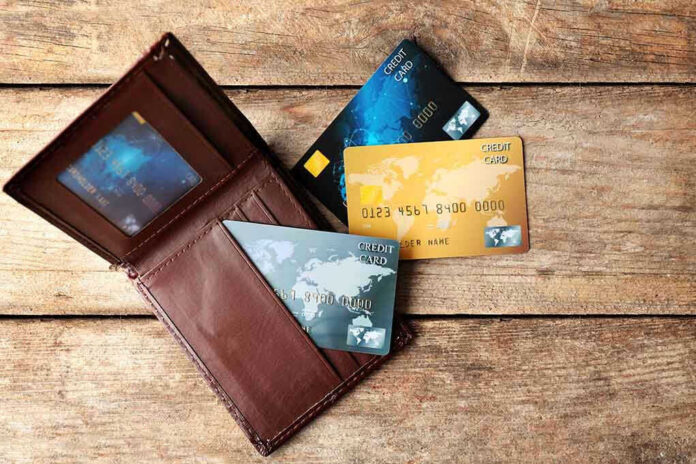 465382001 Wallet with three credit cards on wooden surface