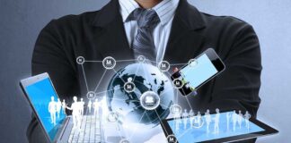 Businessman holding a laptop and tablet with digital icons representing global connectivity