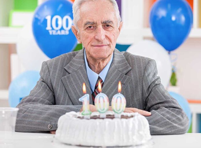 Elderly man celebrating his 100th birthday with a cake and candles