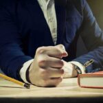 The Reality Behind Glamorous Leadership Titles A mans clenched fist resting on a desk with office supplies nearby