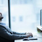 Man sitting at a desk looking up while typing on a computer
