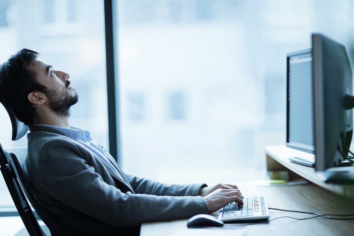 shutterstock_552087472.jpg Man sitting at a desk looking up while typing on a computer