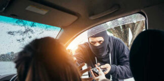 Masked person robbing a woman inside a car.