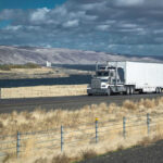 Duffy’s Crackdown SHOCKS Trucking Industry Truck driving on rural highway near river and mountains