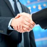 France’s Shocking Ukraine Power Play Two business professionals shaking hands in a corporate setting