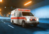 Ambulance driving through a brightly lit tunnel.