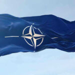 Trump Reshapes NATO — Allies Stunned NATO flag waving against blue sky.