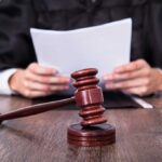 Obama Judge Backs Trump’s Huge Visa Fee A judge holding documents with a gavel in the foreground
