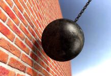 A wrecking ball suspended near a brick wall, suggesting demolition activity
