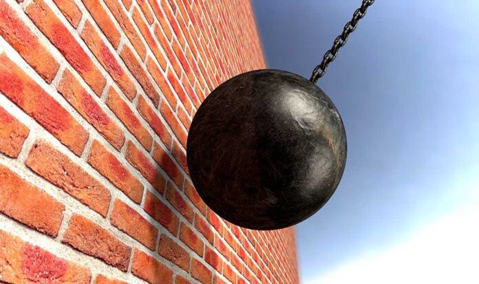 A wrecking ball suspended near a brick wall, suggesting demolition activity