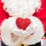 Museum Torches Santa’s White Male Identity Santa Claus holding a red heart in front of a festive background