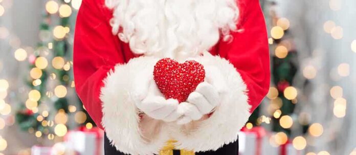 Santa Claus holding a red heart in front of a festive background