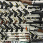Gun Rights Under Fire in New Mexico Wall display with handguns and rifles for sale.