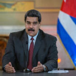 Maduro Caught! Shocking U.S. Military Operation Man speaking at podium with Cuban flag in background.