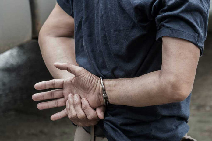 1115333126 Person in handcuffs with hands behind back.