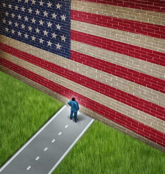 shutterstock_157523579.jpg A man in a suit standing in front of a large American flag painted on a wall