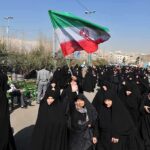 Iran in Turmoil: Supreme Leader’s Secret Escape Group of women in black attire marching with an Iranian flag