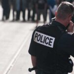 Two Portland Cops GUNNED DOWN — Shooter VANISHED Police officer in uniform communicating with a crowd in an urban setting