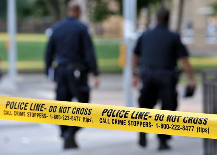 shutterstock_107853224.jpg Police officers walking past caution tape at a crime scene