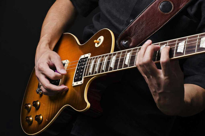 Hands playing an electric guitar.