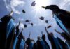Graduating students celebrating by throwing their caps into the air under a bright blue sky