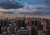 A panoramic view of New York City skyline during sunset with clouds
