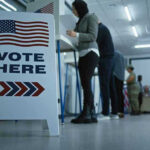 Sign reading Vote Here in a polling station.