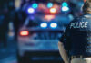 Court Slaps Cops: Guns ≠ Crime Police officer with patrol car and flashing lights.
