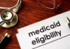 DOJ Drops Bomb on New York’s Democrat Medicaid Deal Stethoscope pen document about Medicaid eligibility on table