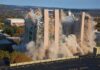 A building being demolished with dust and debris in the air