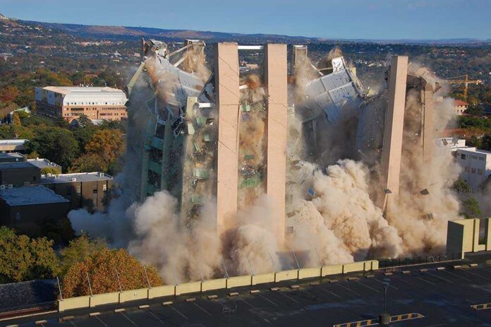 Building,Demolition,By,Implosion,-,Image,7,Of,A,10 A building being demolished with dust and debris in the air