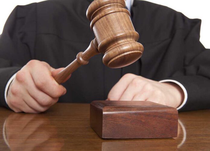 Judge.,Referee,Hammer,And,A,Man,In,Judicial,Robes A judge holding a gavel above a wooden block