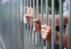 Hidden Prison Release List Sparks Uproar Hands gripping metal prison bars