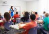 Demographic Whiplash Hits Public Schools Teacher in a blue dress instructing students in a classroom with hands raised