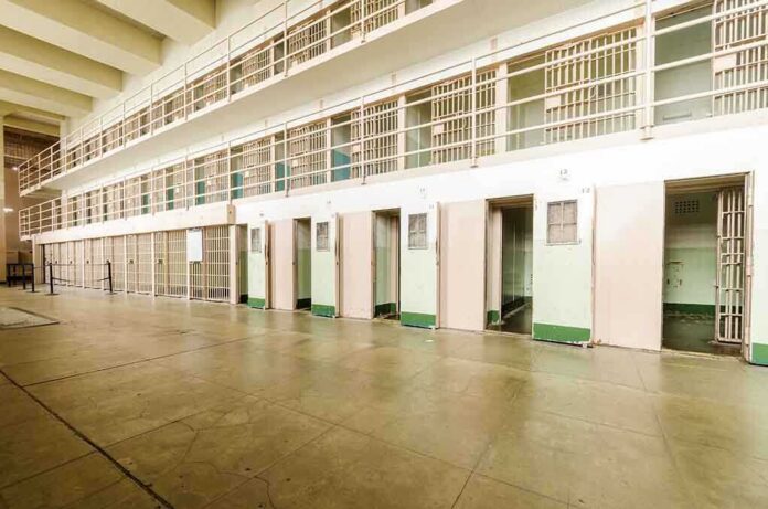shutterstock_206092135 Interior view of a prison cell block with empty cells and security bars