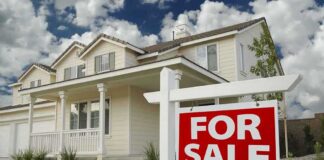 A suburban house with a For Sale sign in the front yard