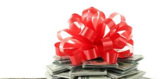 A stack of cash topped with a red ribbon bow