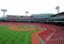 Rainbow Clash Hits MLB Dugout View of an empty Fenway Park baseball stadium with green grass and red seats