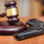 High Court Ducks: Who Gets Handguns? Gavel and handgun on a wooden surface.
