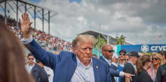 Person in blue suit waving at outdoor event.