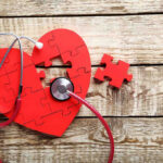 Graham Gone — Truth Drips Out Slowly Red heart puzzle with stethoscope on wooden background.