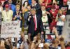 Trump’s Tariff Gambit Rattles Detroit politician on stage at a rally raising a fist amid cheering crowd
