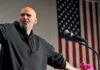 Senator Meltdown Over ‘Pro-Hamas’ Press Bald man speaking at a microphone with a U.S. flag in the background