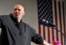 Senator Meltdown Over ‘Pro-Hamas’ Press Bald man speaking at a microphone with a U.S. flag in the background