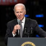 elderly man in suit speaking at a podium