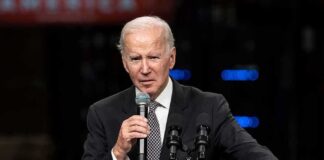 elderly man in suit speaking at a podium