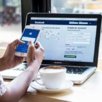 Mandatory ID To Scroll: France Goes First Hands using smartphone with laptop and coffee on cafe table