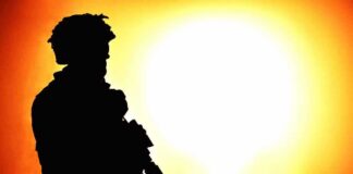 silhouette of an armed soldier against a bright fiery background
